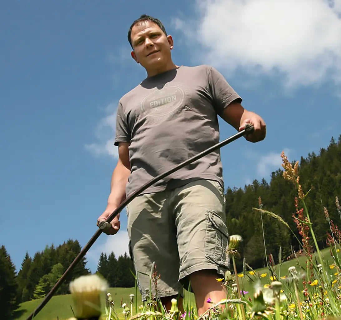 Bauer mit Sense auf Haublumenwiese